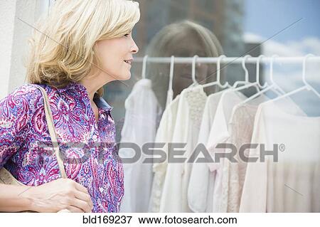 Stock Photo - Caucasian woman shopping in clothing store. Fotosearch