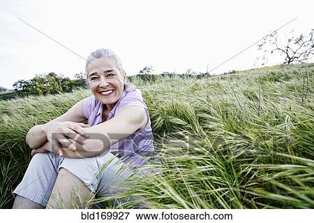 Stock Photo - Caucasian woman sitting in tall grass. Fotosearch