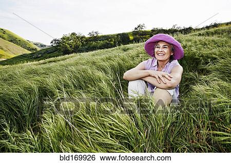 Stock Photograph - Caucasian woman sitting in tall grass. Fotosearch