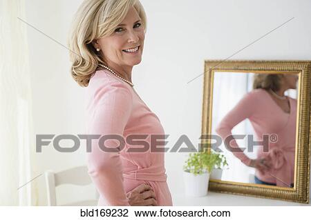 Stock Image - Caucasian woman smiling in mirror. Fotosearch