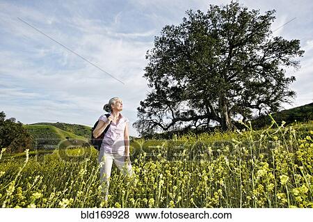 Stock Photo - Caucasian woman standing in tall grass. Fotosearch