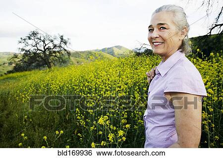 Stock Photograph - Caucasian woman standing in tall grass. Fotosearch