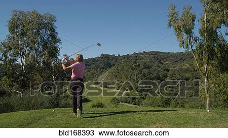 Stock Image - Caucasian woman teeing off on golf course. Fotosearch