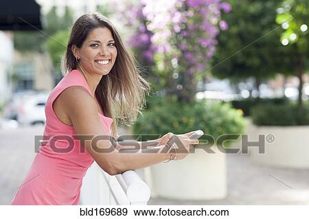 Caucasian woman using cell phone at fence View Large Photo Image Stock Photo - Caucasian woman using cell phone at fence. Fotosearch