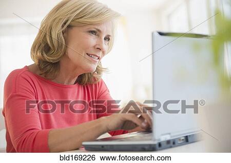 Stock Photograph - Caucasian woman using laptop at desk. Fotosearch