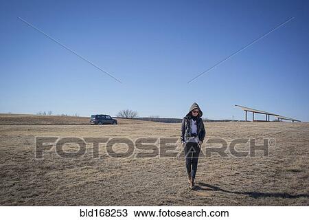 Stock Image - Caucasian woman walking in empty field. Fotosearch