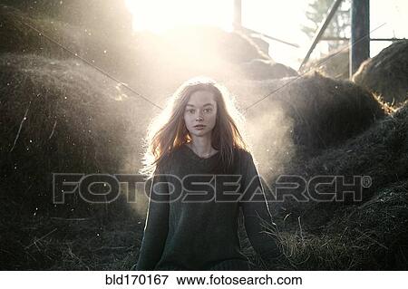 Stock Photo - Caucasian woman walking standing near hay bales on farm. Fotosearch
