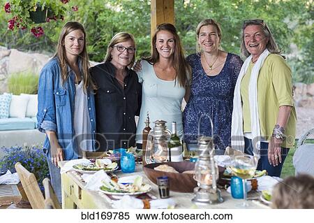 Stock Photography - Caucasian women smiling at table outdoors. Fotosearch
