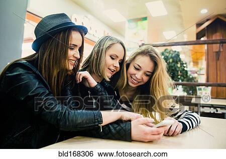 Caucasian women using cell phone in shopping mall View Large Photo Image Stock Photograph - Caucasian women using cell phone in shopping mall. Fotosearch