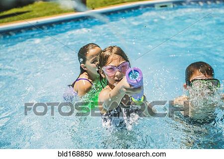 Stock Image - Children playing with squirt gun in swimming pool. Fotosearch