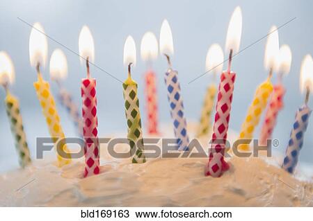 Stock Image - Close up of birthday candles in cake. Fotosearch