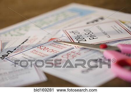 Stock Image - Close up of coupons and scissors on table. Fotosearch