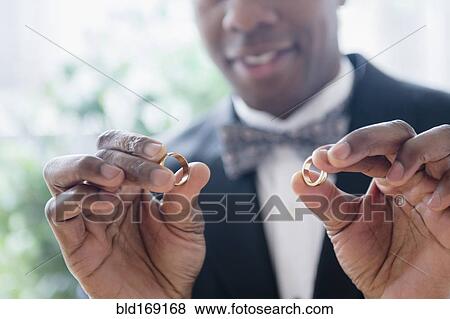 Close up of groom holding wedding rings View Large Photo Image Stock Photo - Close up of groom holding wedding rings. Fotosearch