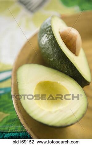 Stock Image - Close up of halved avocado in bowl. Fotosearch