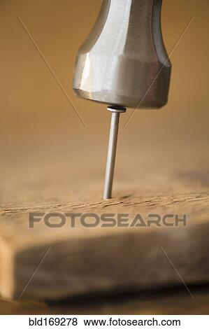 Stock Photo - Close up of hammer and nail in wooden board. Fotosearch
