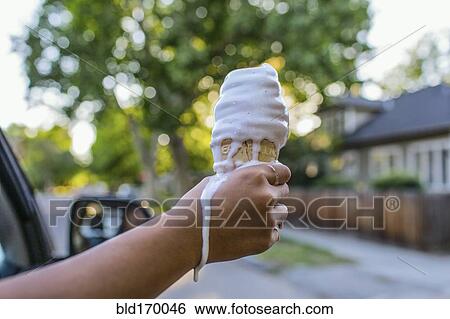 Stock Photograph - Close up of hand of Chinese girl holding melting ice cream cone. Fotosearch
