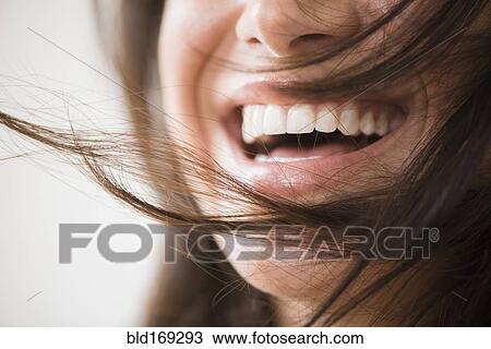Stock Image - Close up of laughing woman with messy hair. Fotosearch