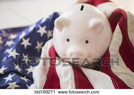Stock Image - Close up of piggy bank and American flag. Fotosearch