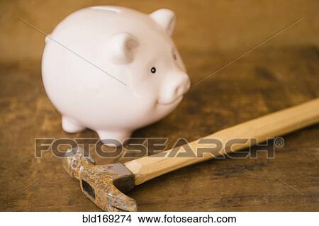 Picture - Close up of piggy bank and hammer on table. Fotosearch