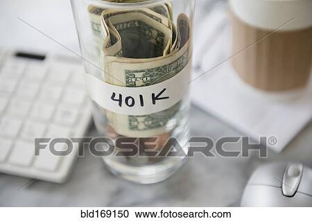 Stock Image - Close up of savings cup on office desk. Fotosearch