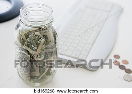 Stock Photo - Close up of savings jar near computer keyboard. Fotosearch