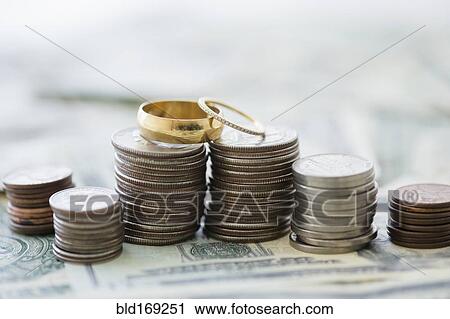 Stock Image - Close up of stacks of coins and wedding rings. Fotosearch