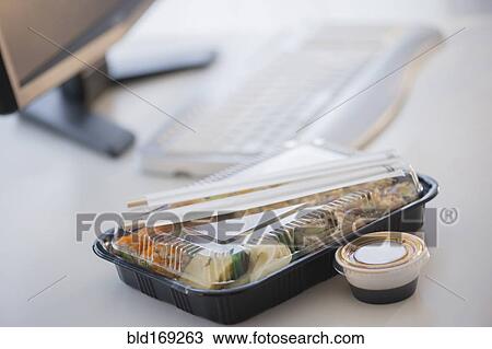 Stock Image - Close up of take-out lunch near computer. Fotosearch