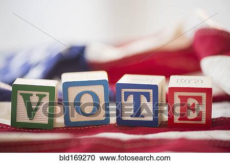 Stock Image - Close up of vote toy blocks on American flag. Fotosearch