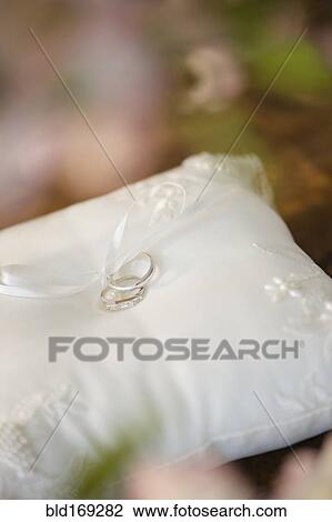 Stock Image - Close up of wedding rings on ring pillow. Fotosearch