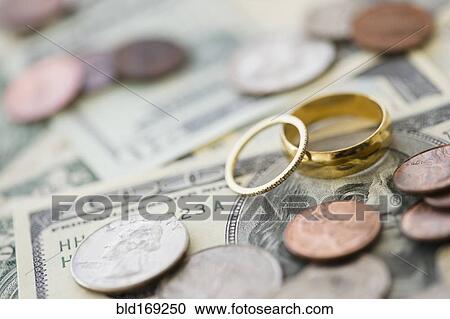 Stock Image - Close up of wedding rings with money. Fotosearch