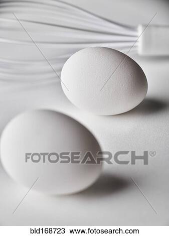 Stock Image - Close up of white whisk and eggs. Fotosearch