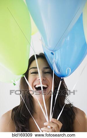 Stock Photo - Close up of woman holding bunch of balloons. Fotosearch