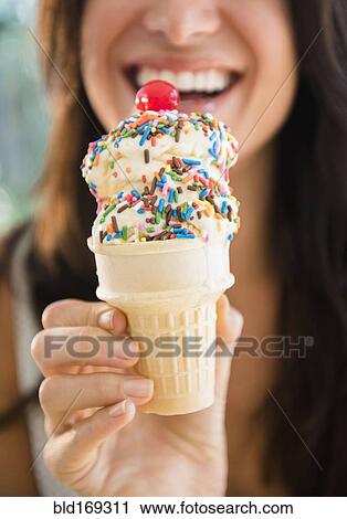 Stock Image - Close up of woman holding ice cream cone. Fotosearch