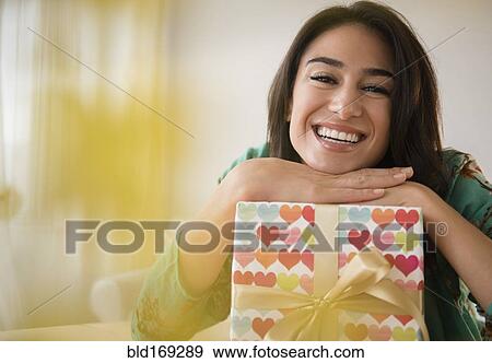 Stock Photo - Close up of woman leaning on wrapped gift. Fotosearch