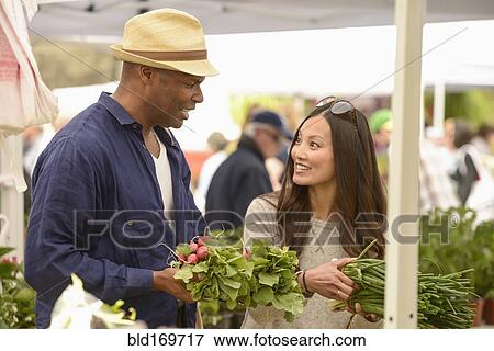 Stock Photo - Couple shopping for produce at farmers market. Fotosearch