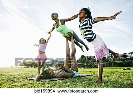 Family practicing acro yoga in park View Large Photo Image Picture - Family practicing acro yoga in park. Fotosearch