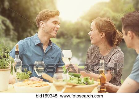 Stock Photography - Friends having dinner party in backyard. Fotosearch