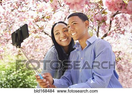 Picture - Friends taking self portrait under flowering tree. Fotosearch