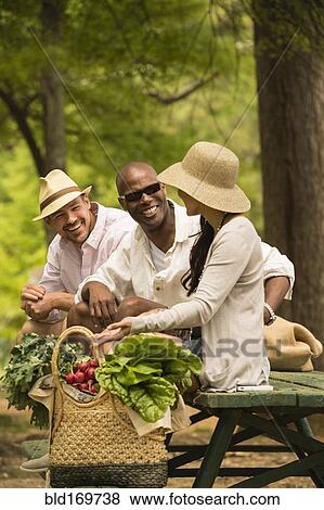 Friends talking on picnic table View Large Photo Image Stock Photo - Friends talking on picnic table. Fotosearch