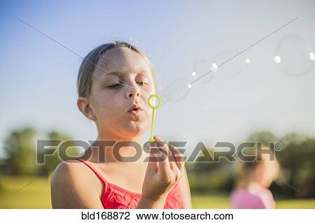 Girl blowing bubbles outdoors View Large Photo Image Stock Image - Girl blowing bubbles outdoors. Fotosearch