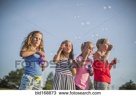 Girls blowing bubbles outdoors View Large Photo Image Stock Image - Girls blowing bubbles outdoors. Fotosearch