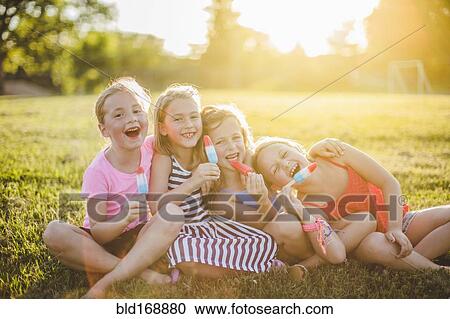 Girls eating flavored ice in sunny field View Large Photo Image Stock Image - Girls eating flavored ice in sunny field. Fotosearch
