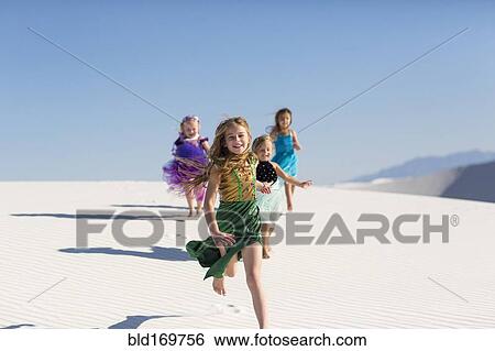 Stock Photograph - Girls running on desert sand dunes. Fotosearch