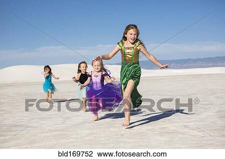 Stock Image - Girls walking on desert sand dunes. Fotosearch
