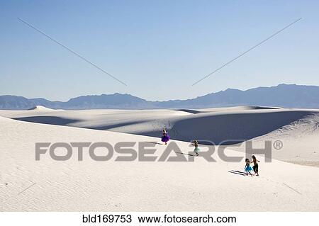 Stock Image - Girls walking on desert sand dunes. Fotosearch