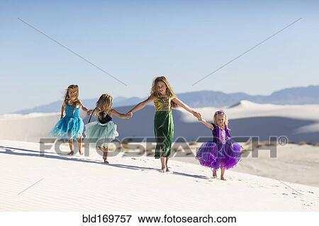 Stock Photo - Girls walking on desert sand dunes. Fotosearch