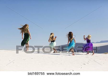 Stock Photography - Girls walking on desert sand dunes. Fotosearch