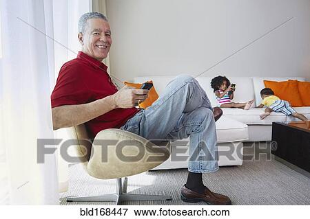 Stock Photo - Grandfather and grandchildren relaxing in living room. Fotosearch