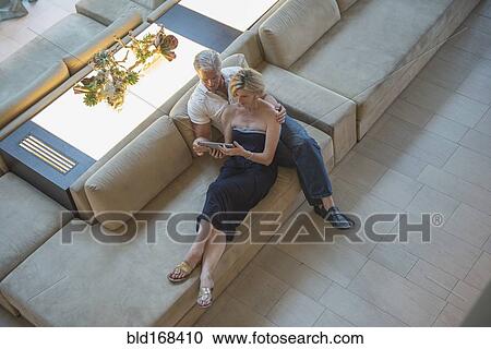 Stock Image - High angle view of Caucasian couple using digital tablet in hotel lobby. Fotosearch