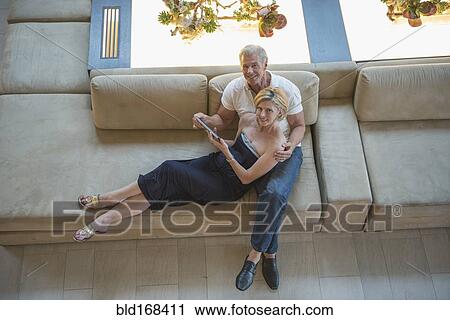 Stock Image - High angle view of Caucasian couple using digital tablet in hotel lobby. Fotosearch